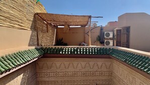 A courtyard with a tiled roof, a thatched structure, and a patterned wall. - Riad Laksiba (Marrakech)