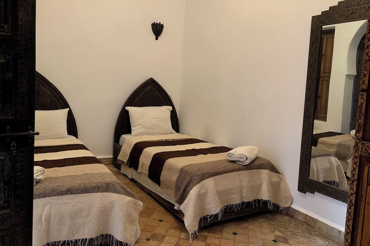 Une chambre avec deux lits, un miroir et un décor mural en forme de cœur.