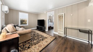 Un salon moderne avec un canapé, un téléviseur et une table basse en verre.
