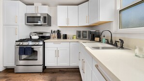 Une cuisine moderne avec des meubles blancs, des appareils en acier inoxydable et un plancher en bois.