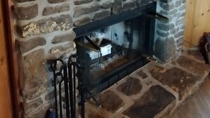 A stone fireplace with a television above it, a wooden ceiling, and a sign that reads "The cabin is my happy place."