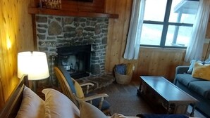 A cozy room with a stone fireplace, a sofa, a table, and a lamp.
