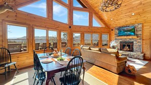 A spacious room with a large dining table, chairs, a sofa, and a fireplace.