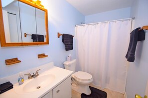 A bathroom with a white sink, a toilet, a shower curtain, and a mirror. - Raffles 206 1 Bedroom Condo by RedAwning (Ocean City)