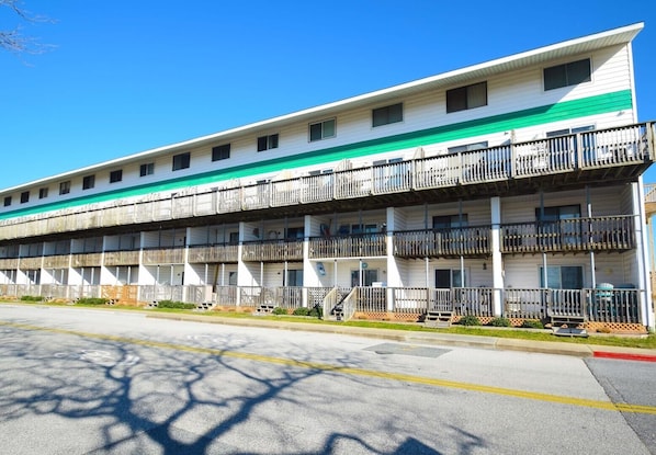 A multi-story motel with balconies, a parking lot, and a clear blue sky. - Raffles 206 1 Bedroom Condo by RedAwning (Ocean City)