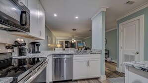 Uma cozinha moderna com armários brancos, eletrodomésticos de aço inoxidável e bancada de mármore.