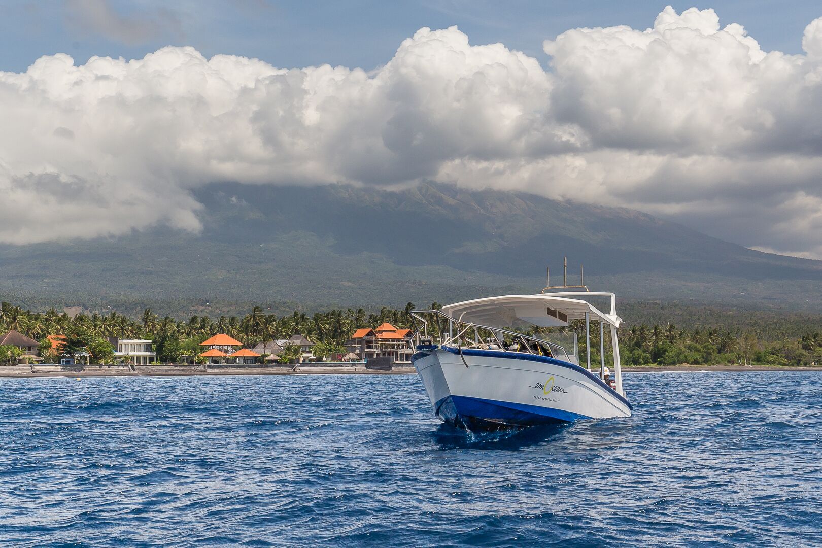 A boat on a body of water with a mountainous landscape and buildings in the background.