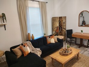 Relax in this inviting living room with a sofa, coffee table, dining area, and large mirror.