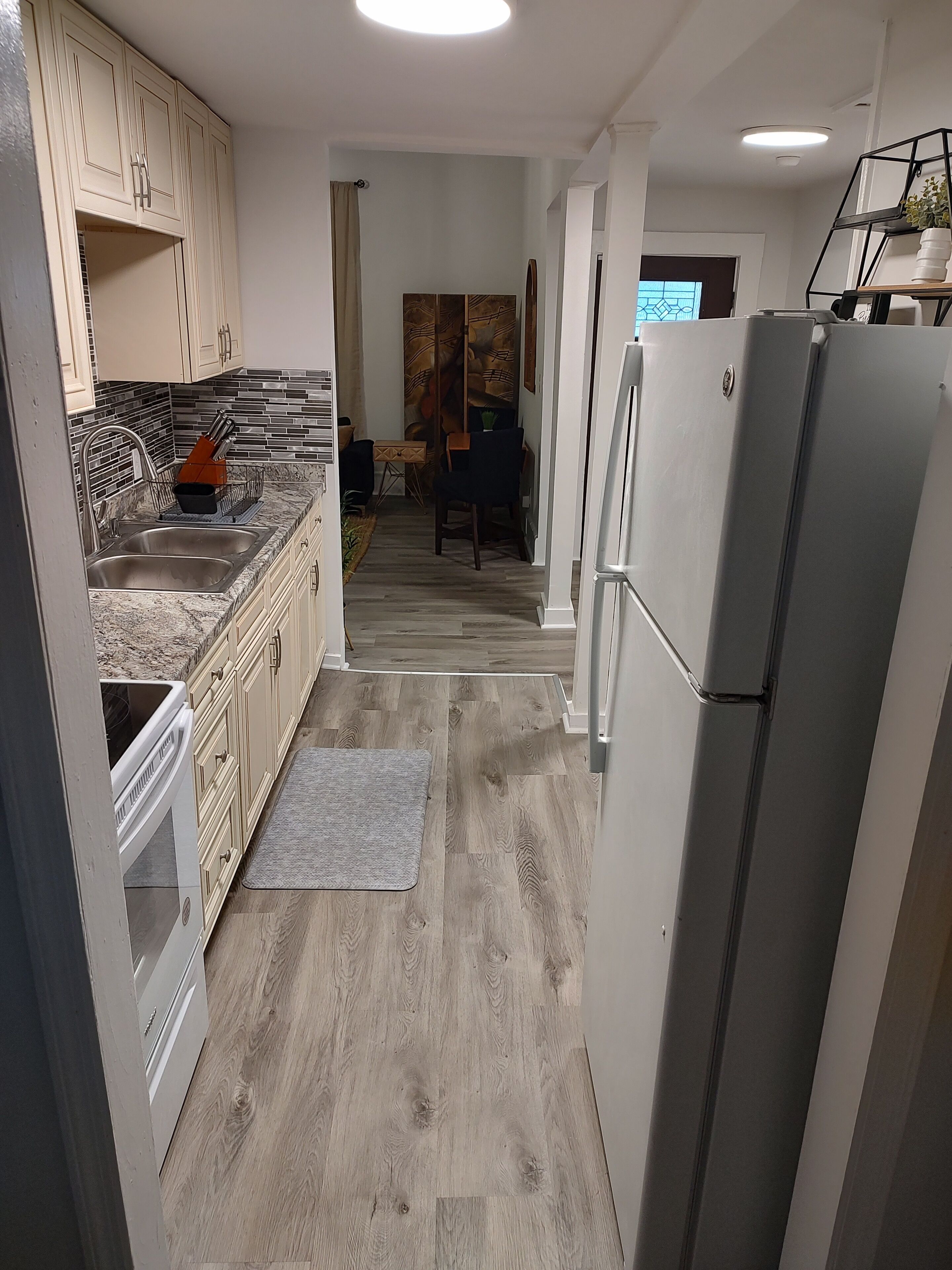 A modern kitchen with a built-in oven, a refrigerator, and a dining area with a table and chairs.