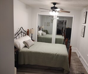 Cozy retreat with a single bed, ceiling fan, and mirror.