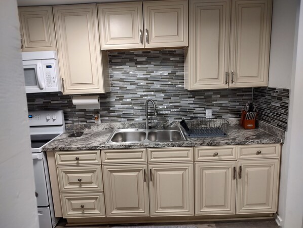 Compact kitchen with double sink, microwave, and oven.
