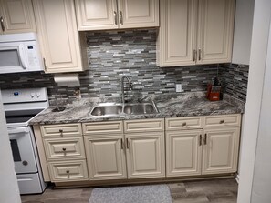 A kitchen with beige cabinets, a granite countertop, a stainless steel sink, and a microwave.