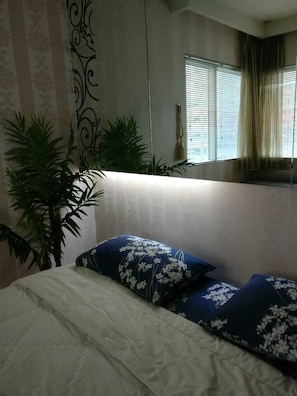Cozy retreat with a plush bed, a potted plant, and a decorative wall piece.