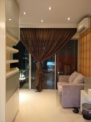 Enjoy a modern living space with a neutral-toned sofa and glass partition offering a view of the outside.