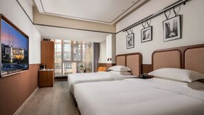 A hotel room with two beds, a large window, and a flat-screen TV.