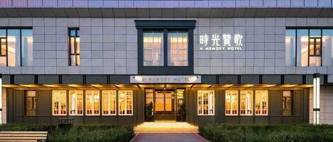 A modern hotel with a sign reading 'A MEMORY HOTEL' and a large entrance with a pathway leading to the doors.