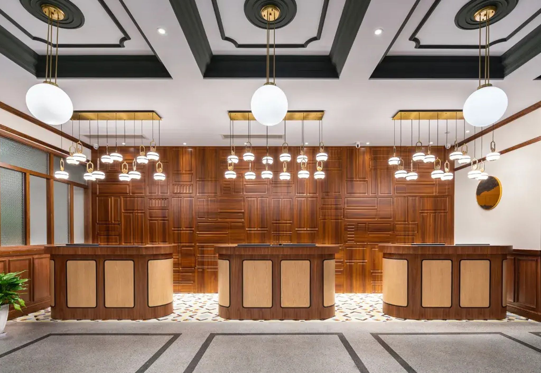 A reception area with a wooden reception desk, hanging pendant lights, and a patterned floor.