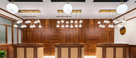 A reception area with a wooden reception desk, hanging pendant lights, and a patterned floor.