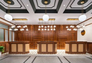 A reception area with a wooden reception desk, hanging pendant lights, and a patterned floor. - A Memory Hotel (Beijing)