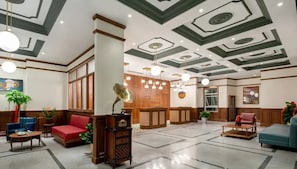 A lobby with a high ceiling, wooden paneling, and a central seating area with a red sofa and blue chairs. - A Memory Hotel (Beijing)
