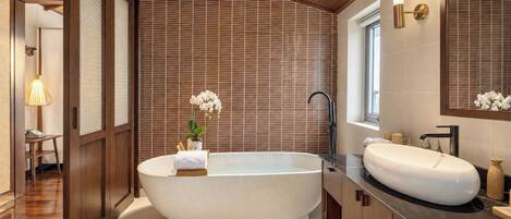 A modern bathroom with a freestanding bathtub, a large mirror, and a wooden floor.