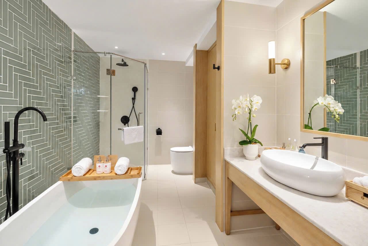 Un baño moderno con una bañera independiente, una ducha con mampara de vidrio y un espejo grande.