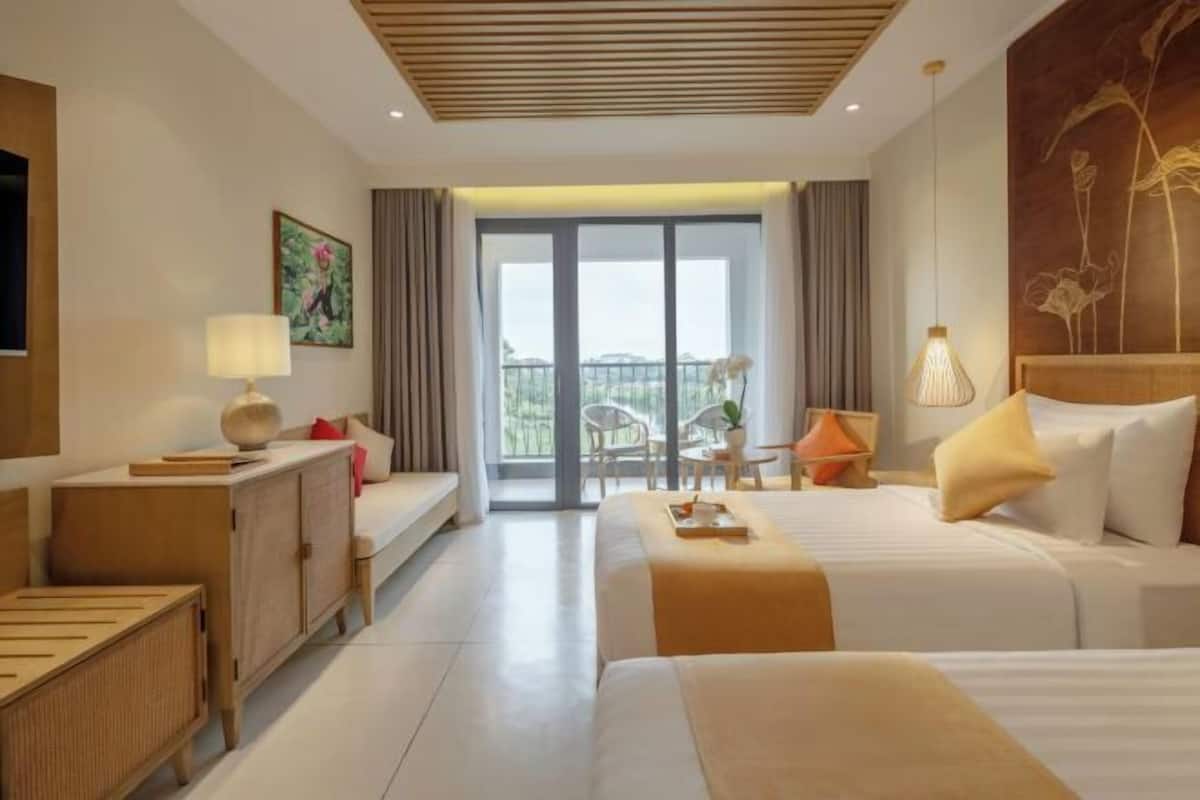 Une chambre d’hôtel avec deux lits, un canapé, un bureau, une chaise, un balcon avec vue et un tableau au mur.