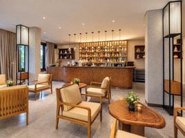 A modern bar area with wooden furniture and a variety of bottles.