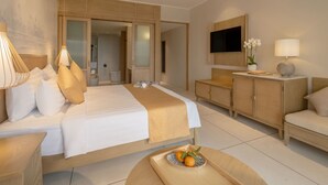 A modern hotel room with a large bed, a TV mounted on the wall, a wooden cabinet, and a small table with a tray of fruit.