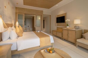 Een moderne hotelkamer met een groot bed, een aan de muur bevestigde televisie, een houten kast en een tafeltje met een schaal fruit.