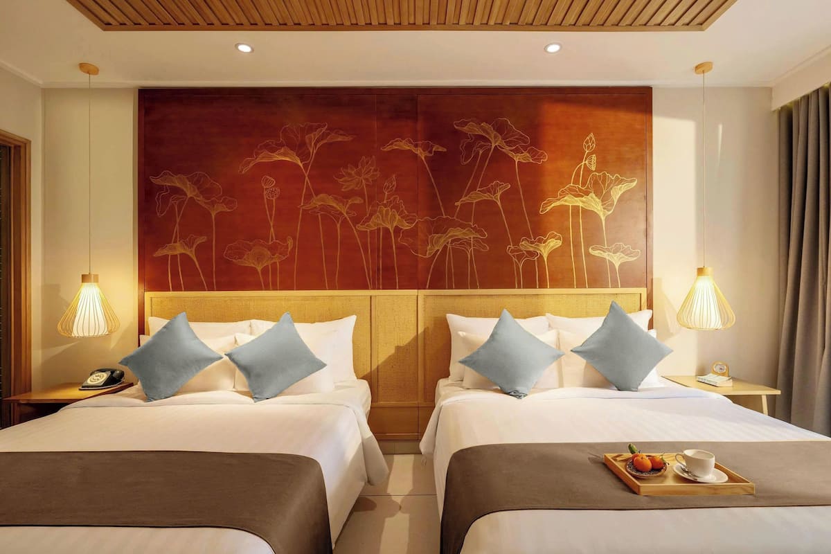 Une chambre d’hôtel avec deux lits, une tête de lit en bois et une grande œuvre d’art florale accrochée au mur.