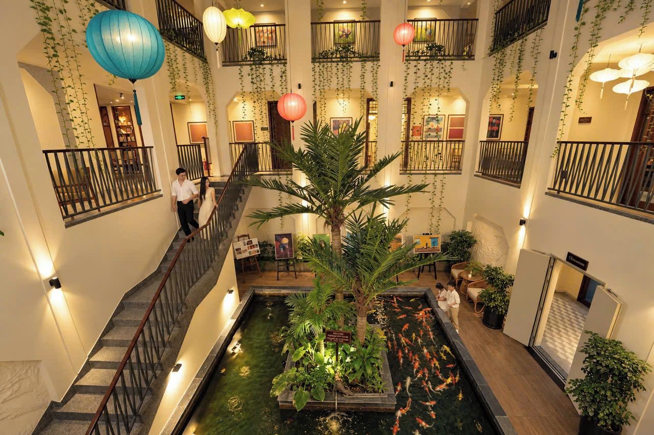 Un vestíbulo de hotel con una fuente central, varios balcones y plantas de interior.