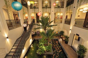 Een hotelatrium met een fontein in het midden, verschillende balkons en kamerplanten.