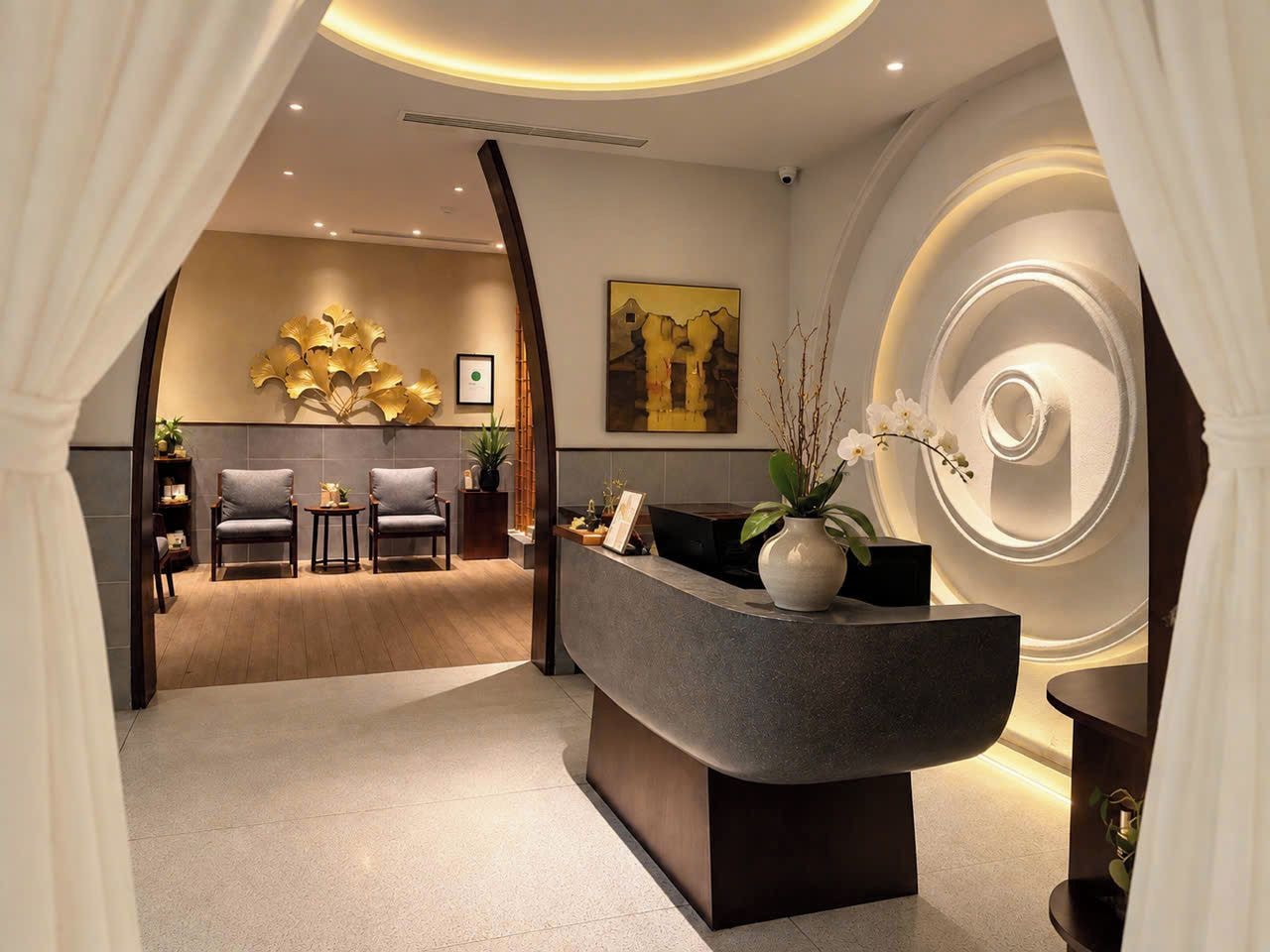 Un área de recepción moderna con un mostrador curvo, zona de estar y una pared decorativa con diseño circular.