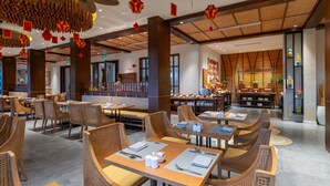 Un restaurant spacieux avec de hauts plafonds, une décoration à base de bambou et un espace buffet.