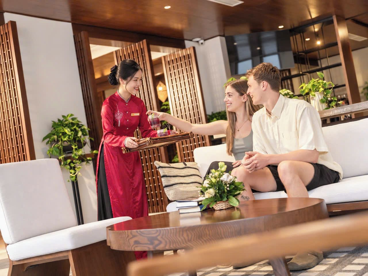 Un vestíbulo de hotel con una zona de estar, una recepción y un camarero sirviendo una bebida.
