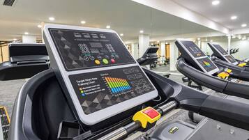 Una cinta de correr con pantalla digital y tabla de entrenamiento de frecuencia cardíaca.