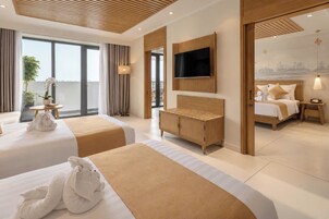 Habitación de hotel con dos camas, televisor, armario de madera y balcón con cortinas.