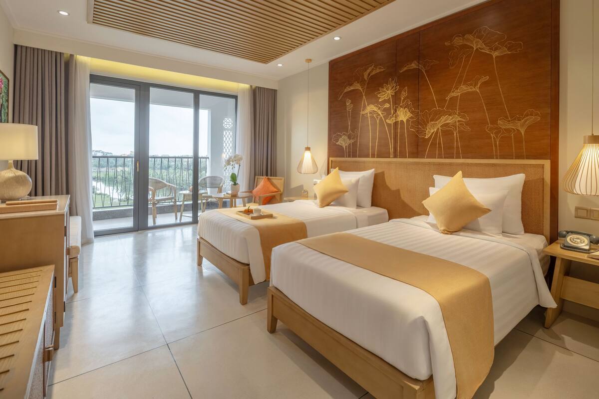 Une chambre d’hôtel avec deux lits, un balcon et une vue sur l’extérieur.