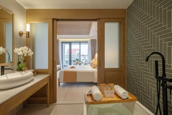 Een moderne hotelbadkamer met een groot wastafel, een houten wastafelmeubel, een bad en een douchehoek.