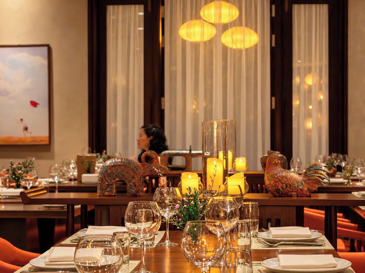A dining area with tables set for a meal, candles, and decorative items.