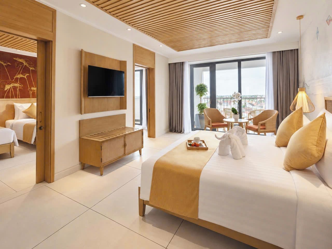 A hotel room with a large bed, a TV, a wooden cabinet, a dining area, and a view of the city.