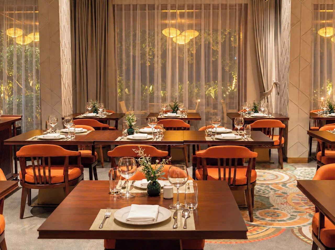 A restaurant with multiple tables, each set with plates, cutlery, and glasses.