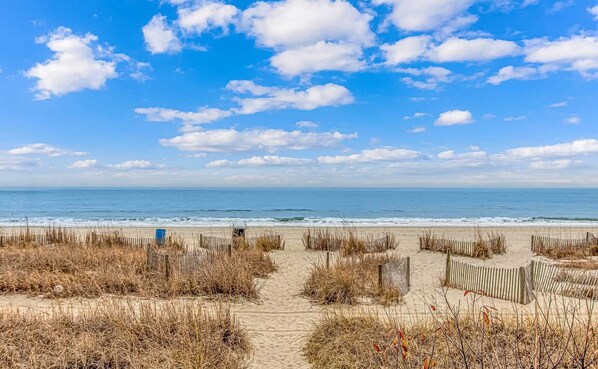 A beach with a wooden fence and a path leading to the water.