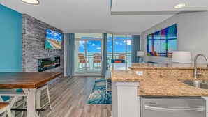 A modern kitchen with a granite countertop, a built-in sink, and a dining area with a wooden table and chairs. - Carolinian 931 (Myrtle Beach)