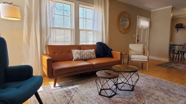 A living room with a brown sofa, a blue armchair, a round coffee table, and a patterned rug.