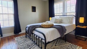 A neatly arranged bedroom with a bed, bedside lamps, and a small wall decoration.