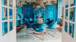 A dining area with a round table, blue chairs, and a chandelier.