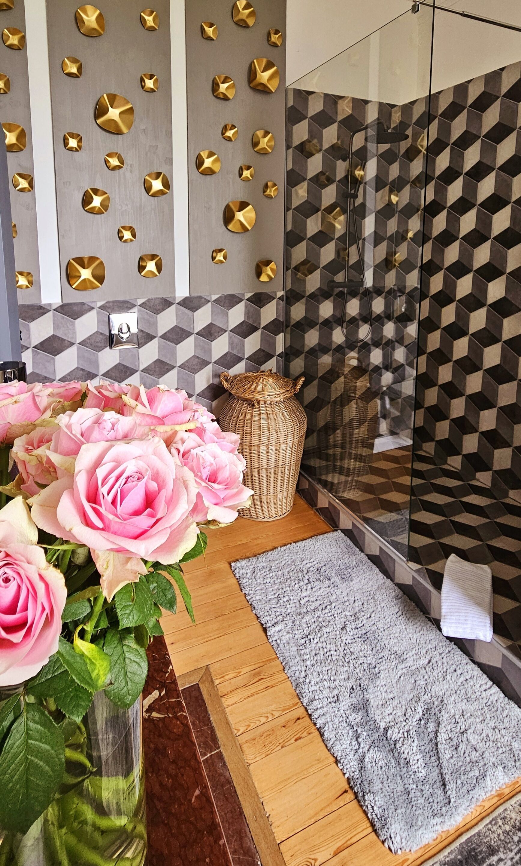 A bathroom with a geometric tile backsplash, a shower area, and a wooden floor.