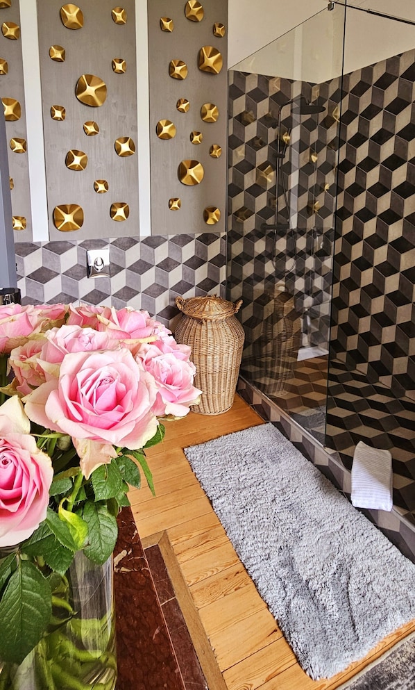 A bathroom with a geometric tile backsplash, a shower area, and a wooden floor. - Chateau Tanesse de Tourny (Bayon-sur-Gironde)